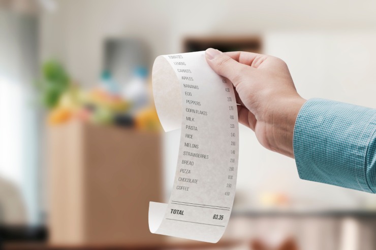 Scontrino in primo piano e sacchetto della spesa alimentare sullo sfondo