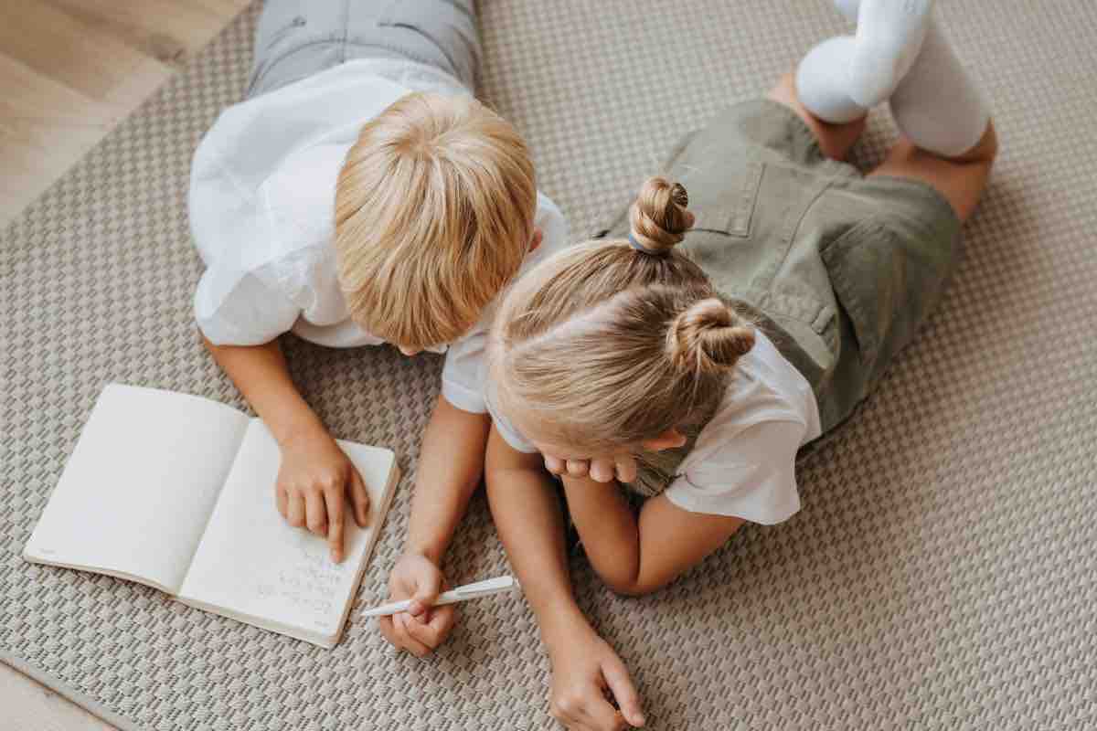 Bambini a terra che fanno i compiti