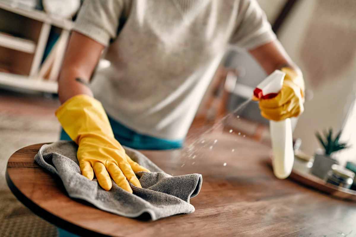 Donna che spruzza prodotto spray sul tavolo