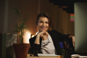 Donna che sorride seduta alla scrivania di sera